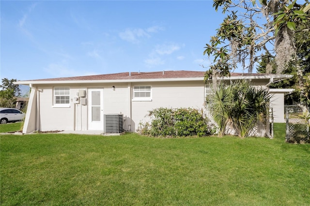 back of property featuring central air condition unit and a yard