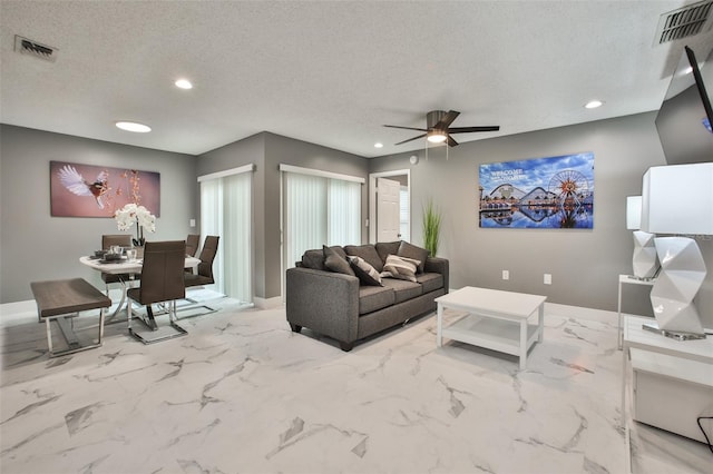 living room featuring ceiling fan and a textured ceiling