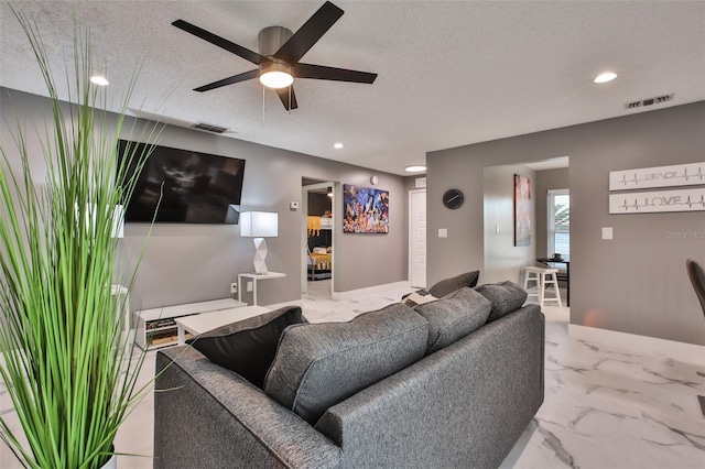 living room featuring ceiling fan and a textured ceiling