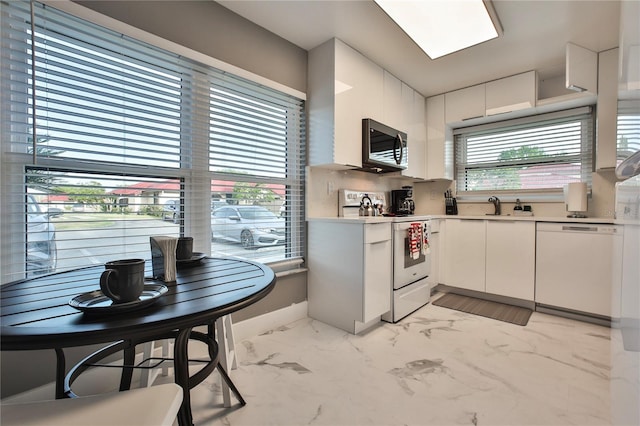 kitchen with white cabinetry, sink, white appliances, and a wealth of natural light