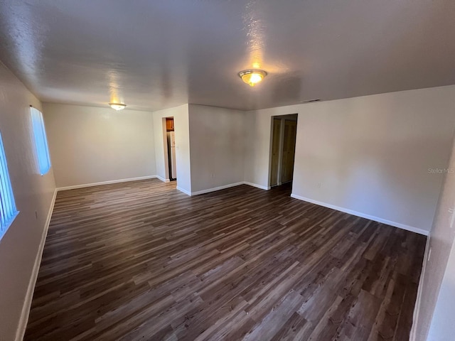 empty room with dark hardwood / wood-style flooring