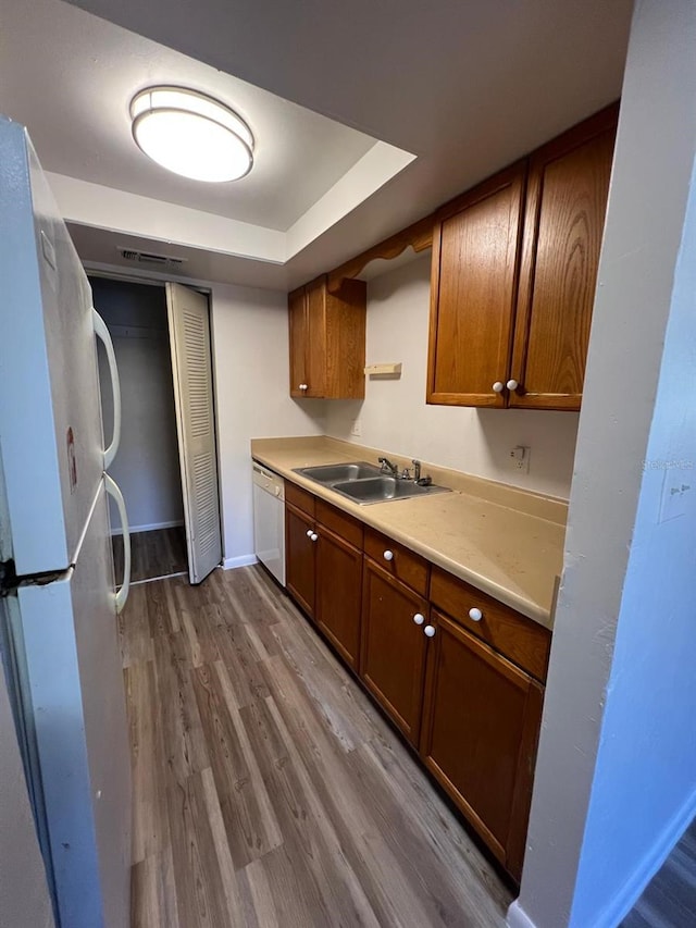 kitchen with sink, white appliances, and hardwood / wood-style floors