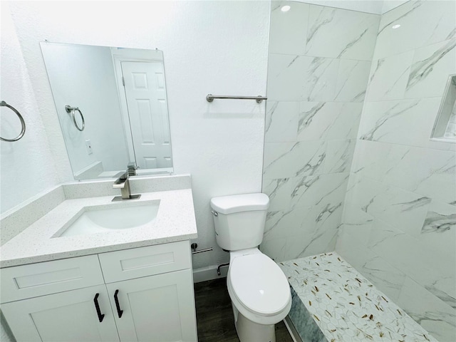 bathroom featuring vanity, hardwood / wood-style flooring, toilet, and a tile shower