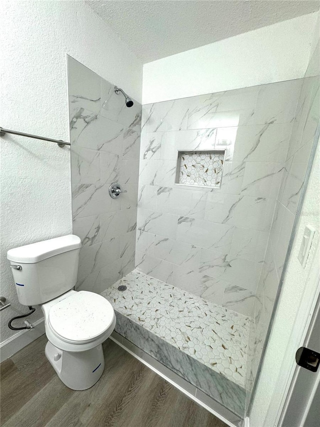 bathroom featuring tiled shower, wood-type flooring, and toilet