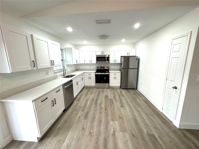 kitchen featuring white cabinetry, appliances with stainless steel finishes, sink, and light wood-type flooring