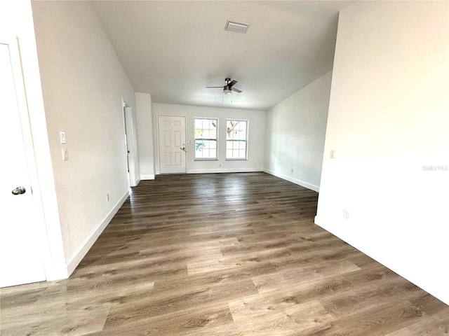 unfurnished living room featuring dark wood-type flooring and ceiling fan