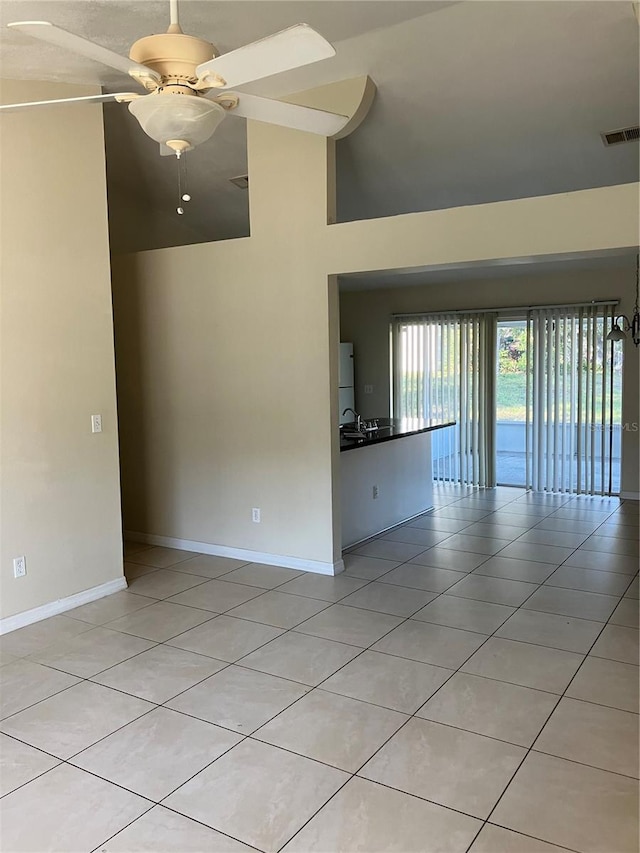 empty room with lofted ceiling, sink, ceiling fan, and light tile patterned flooring