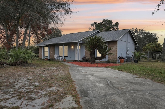 ranch-style house featuring cooling unit, a lawn, and covered porch