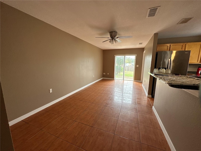 interior space with tile patterned flooring, visible vents, ceiling fan, and baseboards