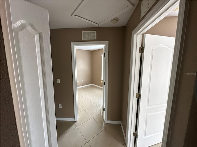 hallway with visible vents, baseboards, and light tile patterned floors