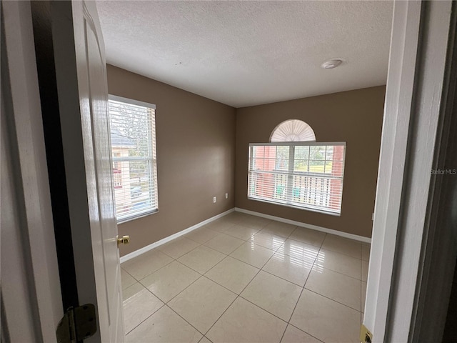 unfurnished room featuring light tile patterned floors, baseboards, and a textured ceiling