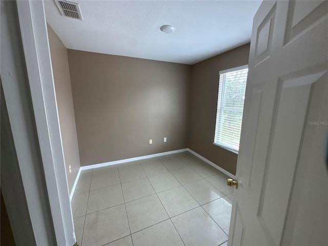 unfurnished bedroom featuring light tile patterned floors, visible vents, baseboards, and a textured ceiling