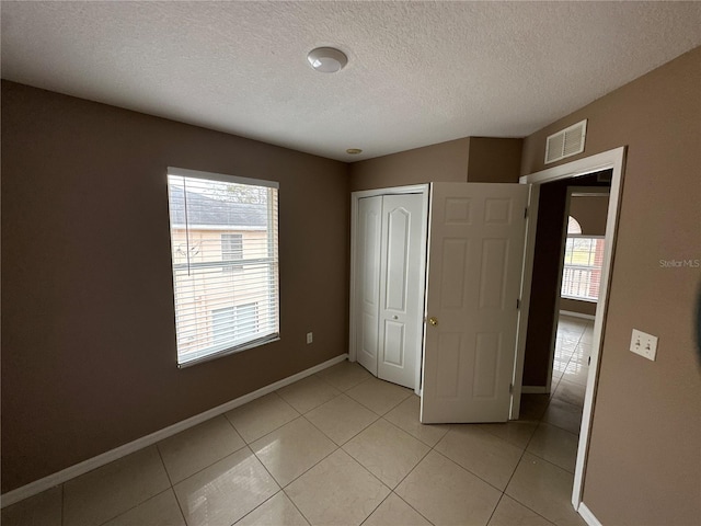 unfurnished bedroom with baseboards, multiple windows, visible vents, and light tile patterned flooring