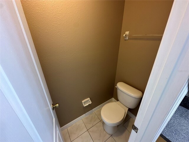 bathroom with tile patterned flooring, toilet, and baseboards