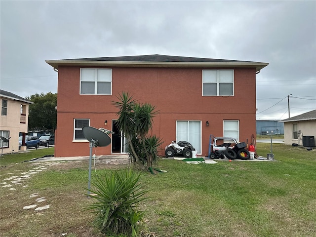 rear view of property featuring a yard, cooling unit, and stucco siding