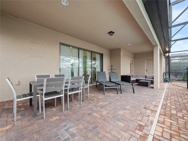 view of patio featuring outdoor lounge area and glass enclosure