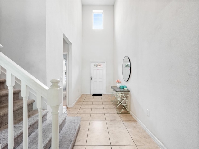 foyer entrance featuring light tile patterned flooring and a towering ceiling