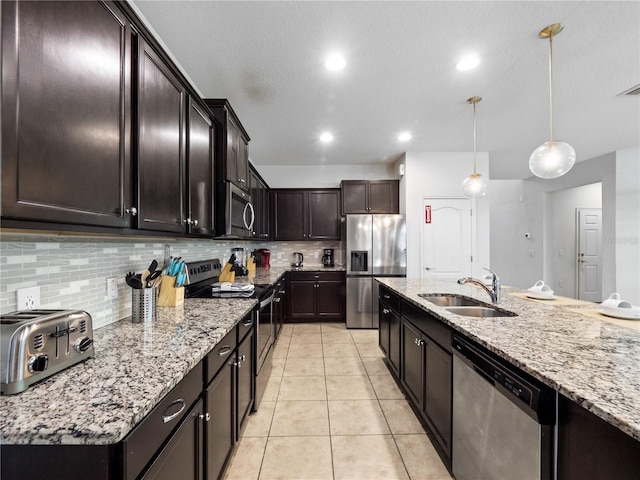 kitchen with pendant lighting, sink, appliances with stainless steel finishes, dark brown cabinets, and decorative backsplash