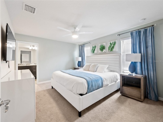 bedroom featuring ensuite bath, light colored carpet, and ceiling fan