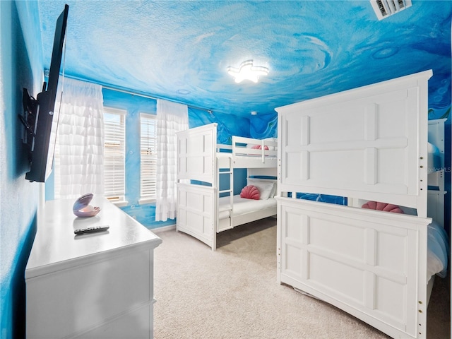 bedroom with light colored carpet and a textured ceiling