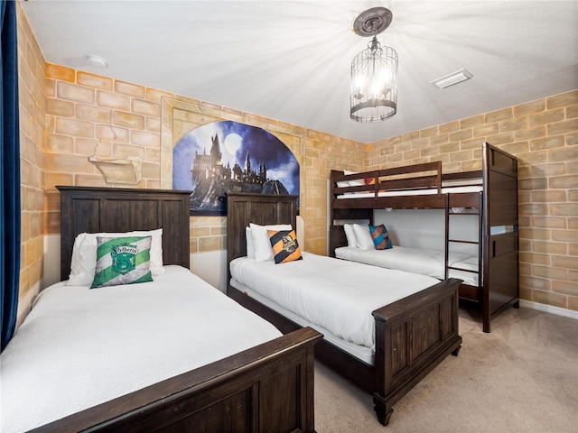 carpeted bedroom with an inviting chandelier and brick wall