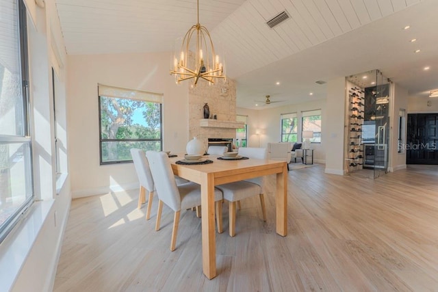 dining room with lofted ceiling, wood ceiling, light hardwood / wood-style floors, and a stone fireplace