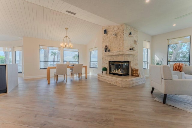 living room featuring a stone fireplace, a healthy amount of sunlight, an inviting chandelier, and wood ceiling