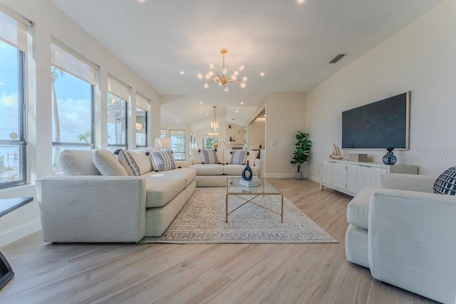 living room with vaulted ceiling, a notable chandelier, and light hardwood / wood-style floors