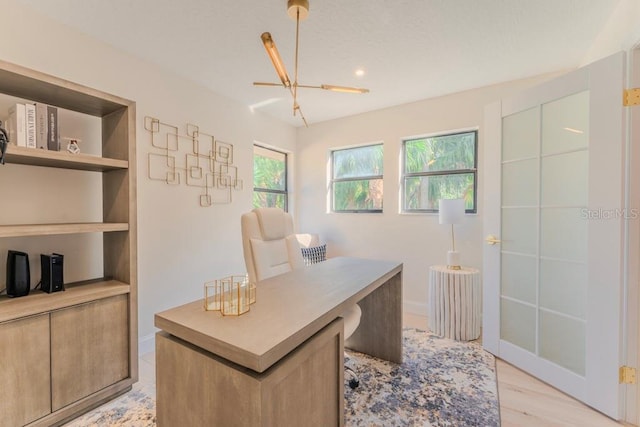 office featuring built in shelves, a healthy amount of sunlight, and light hardwood / wood-style flooring