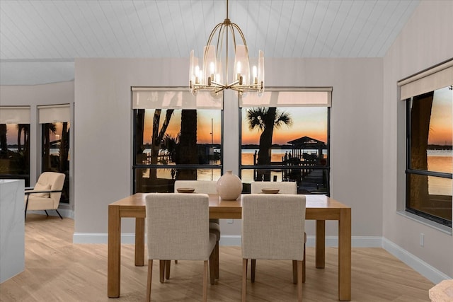 dining area with light wood-type flooring, wood ceiling, and an inviting chandelier