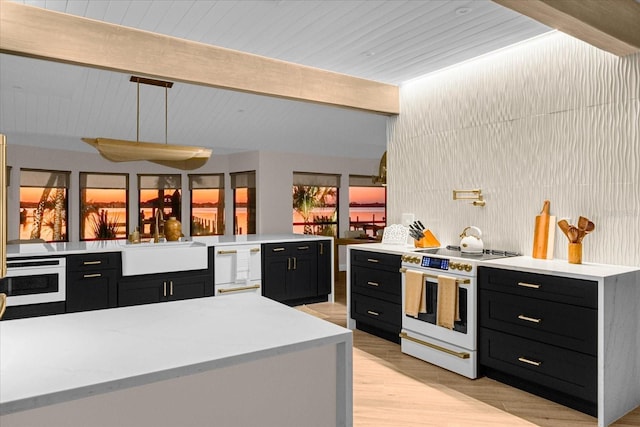 kitchen with sink, white appliances, decorative light fixtures, kitchen peninsula, and beamed ceiling