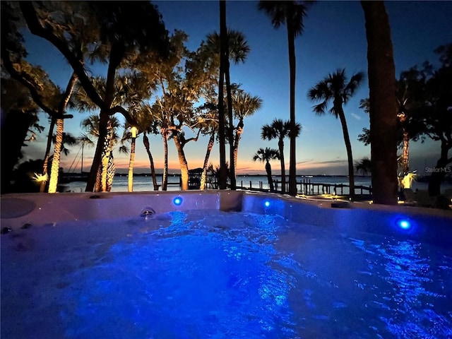 pool at dusk featuring a water view