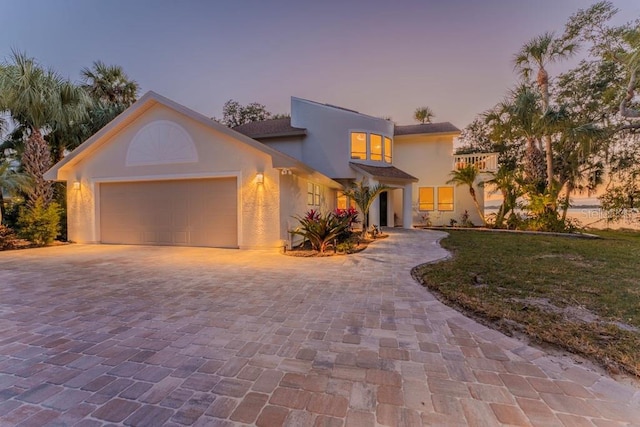 view of front of property featuring a balcony, a garage, and a lawn