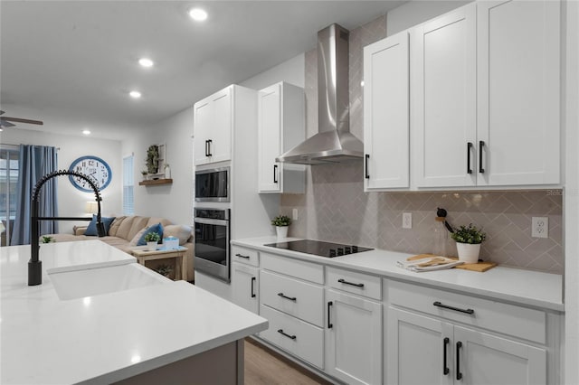 kitchen with white cabinetry, wall chimney exhaust hood, and appliances with stainless steel finishes