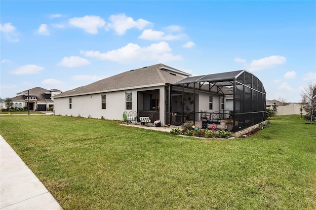 rear view of house with a patio area, glass enclosure, and a lawn