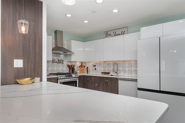 kitchen featuring sink, white cabinetry, stainless steel appliances, decorative backsplash, and wall chimney range hood