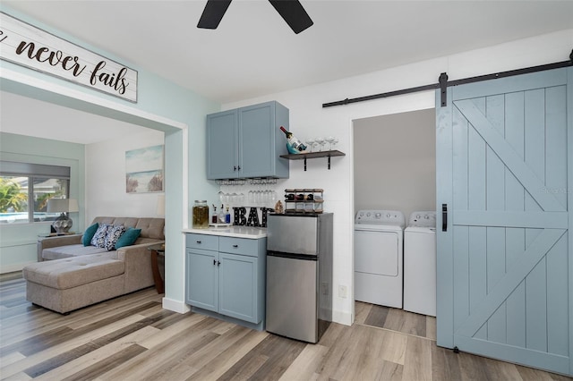 kitchen featuring separate washer and dryer, stainless steel refrigerator, a barn door, light hardwood / wood-style floors, and backsplash