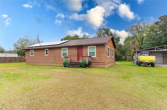 back of property with a carport, a yard, and solar panels