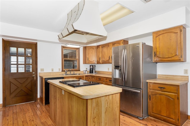 kitchen with a kitchen island, sink, island exhaust hood, light hardwood / wood-style floors, and black appliances