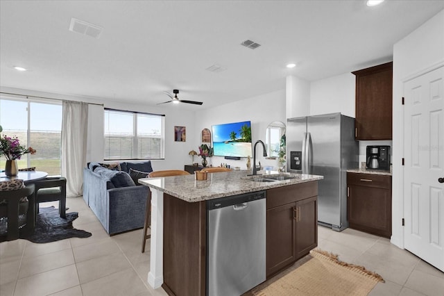 kitchen with a center island with sink, stainless steel appliances, visible vents, open floor plan, and a sink