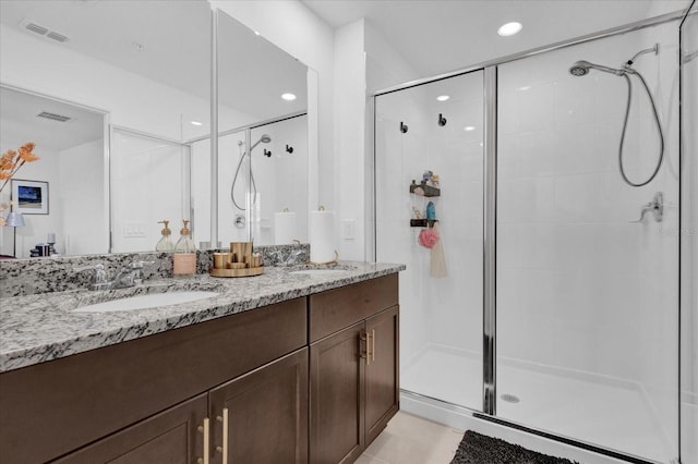 full bath featuring a stall shower, visible vents, a sink, and double vanity