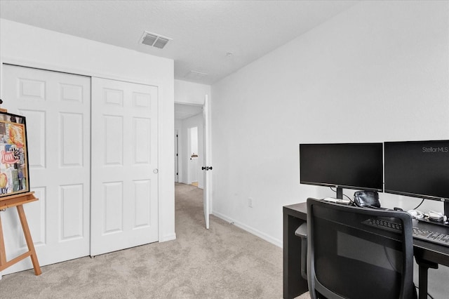 office area featuring baseboards, visible vents, and light colored carpet