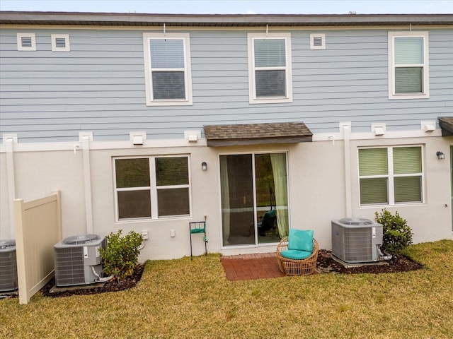 rear view of property featuring stucco siding, a lawn, and central AC unit