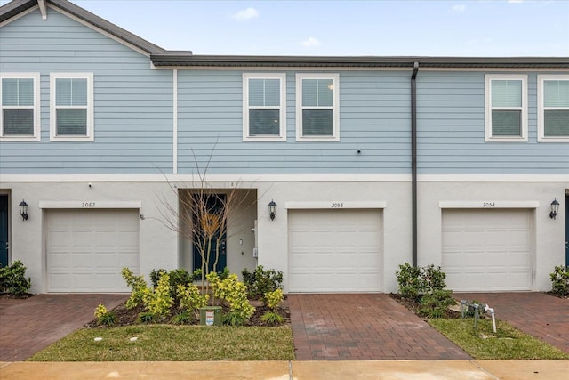 view of property featuring driveway, an attached garage, and stucco siding