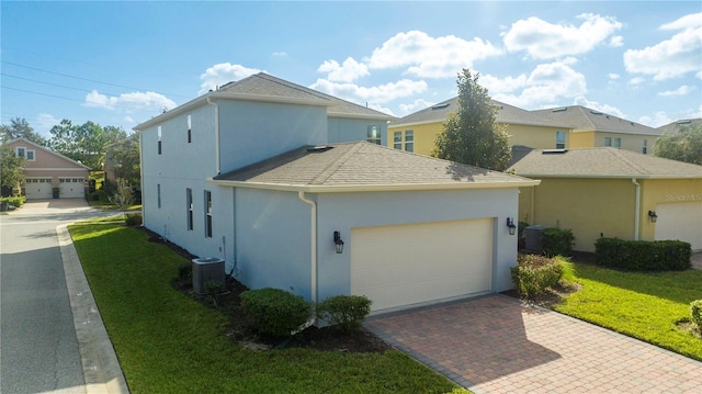 view of front facade with a garage, central AC unit, and a front lawn