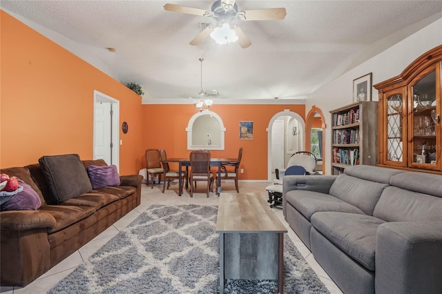 living room featuring light tile patterned flooring, lofted ceiling, ceiling fan, and a textured ceiling