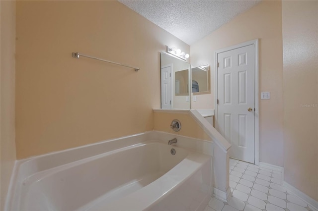 bathroom with tile patterned flooring, vaulted ceiling, a tub, and a textured ceiling