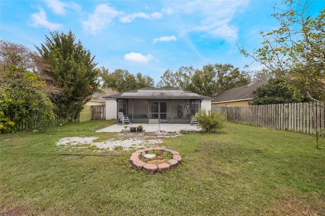 rear view of house featuring a fire pit, a patio area, a sunroom, and a lawn