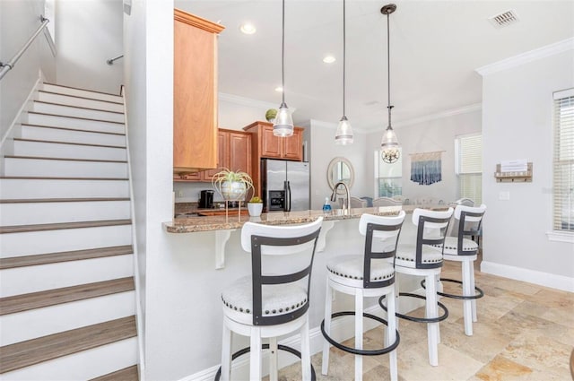 kitchen with visible vents, hanging light fixtures, ornamental molding, light stone countertops, and stainless steel fridge with ice dispenser