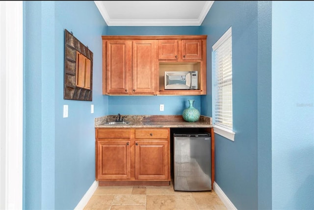 interior space with stainless steel microwave, fridge, a sink, and crown molding